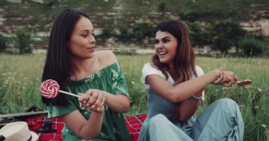 Komik bir lolipop kamera önünde piknik ile oynarken güzel bir gülümseme ile iki kız