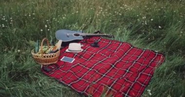 Doğanın bir piknik battaniye bir gıda sepeti gitar tablet ve fotoğraf kamera ile orta.
