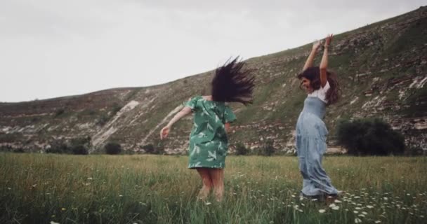 Saltando en medio del paisaje dos chicas guapas — Vídeos de Stock