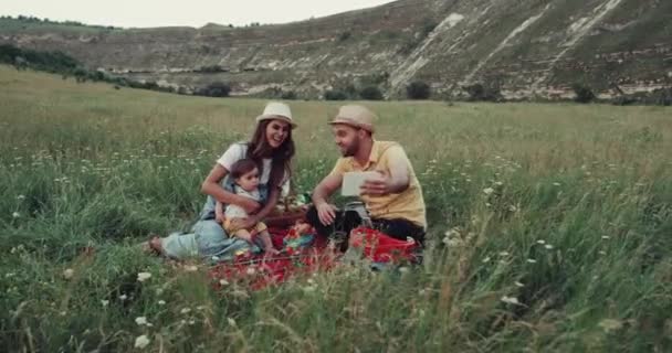 Familie picknick tijd in het midden van de berg, met behulp van een tablet met iemand spreken. — Stockvideo