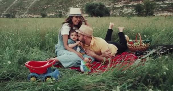 年轻的家庭与一个小男孩花惊人的时间一起在野餐, 玩对方. — 图库视频影像