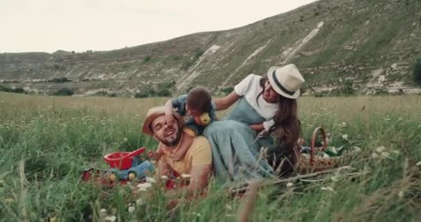 Los padres jóvenes pasan un buen rato con sus hijos en el picnic. — Vídeos de Stock