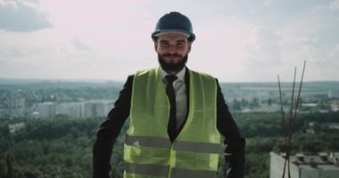 Kameranın üst kısmında bina inşaat alanı içine bakmak genç mühendis gülümseyen.