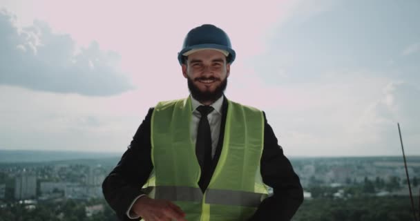 Jovem empresário feliz no topo do canteiro de obras sorrindo olhando direto para a câmera — Vídeo de Stock