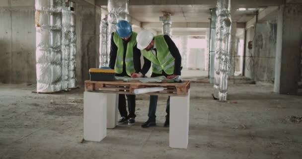 Two expert engineers analyze the map of construction site.4k — Stock Video