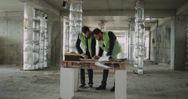 Dos jóvenes arquitectos haciendo un plan de trabajo para la obra . — Vídeos de Stock