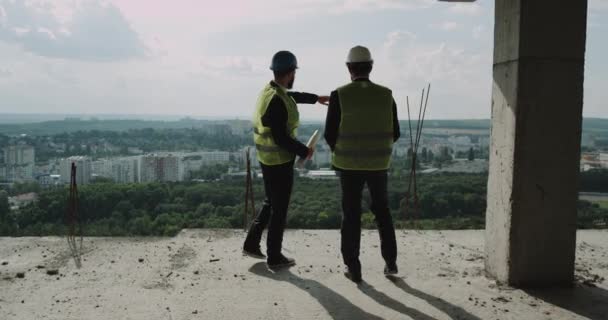Dois jovens trabalhadores da construção olhando através do edifício e ter uma discussão . — Vídeo de Stock