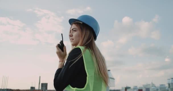 Young woman worker from construction site using a black radio to speak with someone. — Stock Video