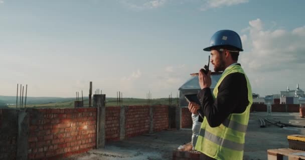 Dzień pracy witryny budowy na dachu budynku inżyniera informatyki analizując mapę budowlane — Wideo stockowe