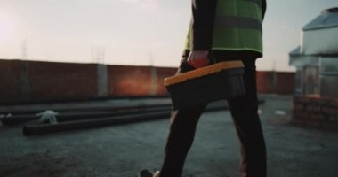 Closeup inşaat sitesi Oluşturucu ya da mühendis bir emanet yelek giyen bir enstrüman ihale şaşırtıcı günbatımı görmek için yürüyüş.