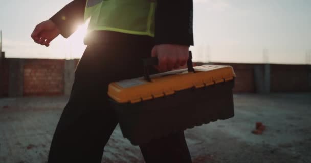 Gros plan constructeur expert venant à son bureau en mettant son sac d'instrument sur le bureau, il porte un gilet de sécurité. au ralenti — Video