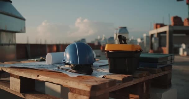 Primo piano nel tetto dell'edificio, scrivania con piano di costruzione, radio e casco di sicurezza . — Video Stock