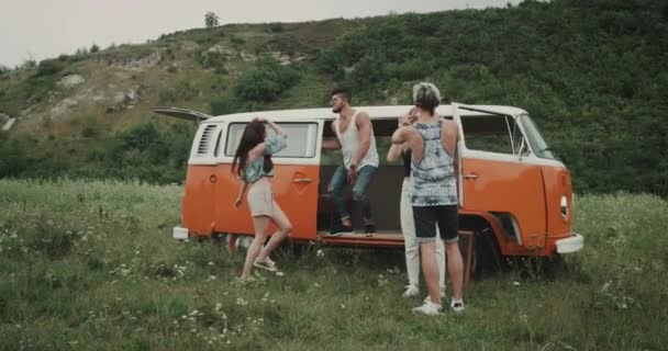 Two couple have fun and dancing in the middle of landscape at picnic time, hip friends and retro bus. 4k — стоковое видео