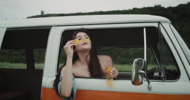 Hippy girl in retro bus blows bubbles, 90s vibe. — Stock Video