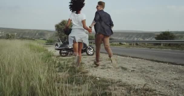 Mädchen und Junge joggen auf ein Motorrad zu und fahren auf einen neuen Weg. Zeitlupe — Stockvideo