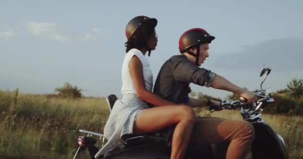 À noite, com uma bela vista do pôr do sol, um casal está andando de moto . — Vídeo de Stock