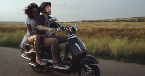 Un beau couple amoureux est en vélo sur la route et le haut blanc des filles est ondulé par le vent doux de l'été. 4k — Video