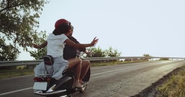 Gadis di sepeda motor melambaikan tangannya ke udara semua bersemangat terjadi pada jarak jauh perjalanan dengan kekasihnya — Stok Video