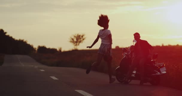 Pasangan yang baik bertemu di tengah jalan dengan matahari terbenam yang menakjubkan, memegang satu sama lain di belakang motor retro mereka. gerakan lambat — Stok Video