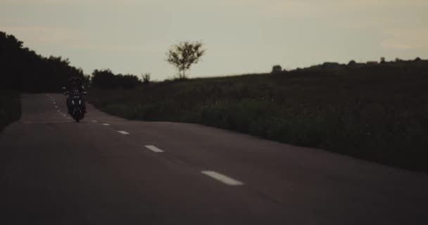 Evening time couple have a ride on the road on their retro black motorbike , they have happy faces wearing a helmet. — Stock Video