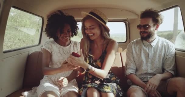 Retro-stylowe przyjaciół, dwie perfekcyjnie dziewczyny z pięknym uśmiechem i jednego człowieka na drodze w autobusie retro patrząc przez telefon, mają szczęśliwe twarze. powolne ruchy. 4k — Wideo stockowe