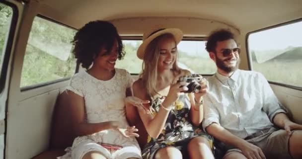 Dos chicas con un vestido retro y un tipo con las gafas que van en el autobús retro tomando fotos usando una cámara fotográfica retro. mociones lentas — Vídeo de stock