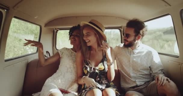 Due ragazze boho alla moda e un ragazzo con gli occhiali e capelli ricci che vanno sul bus vintage, guardando attraverso il finestrino, sono carismatici e molto bello . — Video Stock