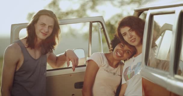 Κομψό νέους φίλους, δύο κυρίες και έναν άντρα σταθεί δίπλα της ένα αναδρομικό λεωφορείο, χαμογελώντας πρόσφατη ευθεία στη φωτογραφική μηχανή. 4k — Αρχείο Βίντεο