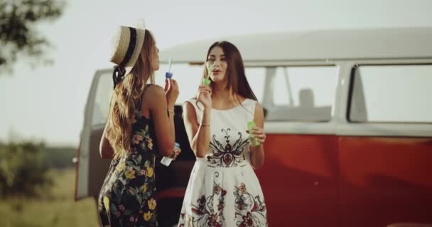 Zwei gut gelaunte Damen, die in einem stylischen Retro-Kleid eine schöne Zeit miteinander verbringen, stehen neben einem schönen Retro-Bus. 4k — Stockvideo