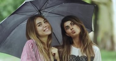 Bayanlar yağmur gün kameraya düz seyir ve komik surat şemsiyesi altında.