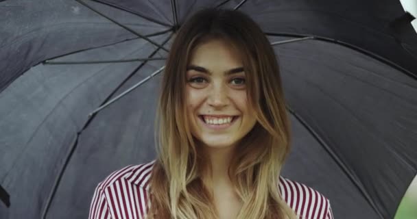 Retrato de cerca de una hermosa chica sonriente bajo el paraguas . — Vídeo de stock