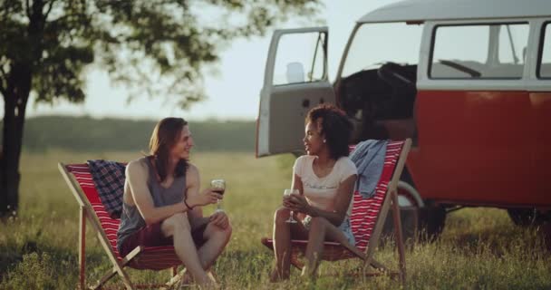 Twee raciale vrienden man en vrouw hebben een vergadering tijd picknick midden in de natuur, met geweldig uitzicht drinken van wijn en glimlachend zittend op houten stoelen. — Stockvideo