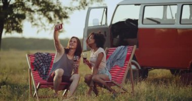 Güzel çift, içme şarap, alma selfies, arka plan inanılmaz retro van ahşap sandalye üzerinde oturan güzel gökyüzü altında inanılmaz yer piknik vakit var.
