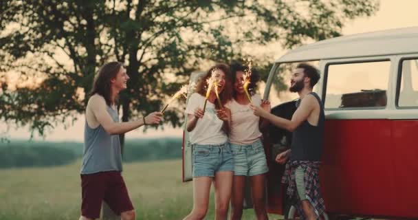 Amigos multiculturales con estilo y hermoso disfrutando del tiempo juntos en la naturaleza, sosteniendo los bengalas y jugando con ellos tienen una sonriente y feliz faces.slow motions — Vídeo de stock