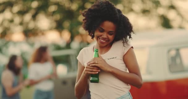 Africana giovane donna al picnic in possesso di una bottiglia di birra sorridente felice guardando la fotocamera — Video Stock