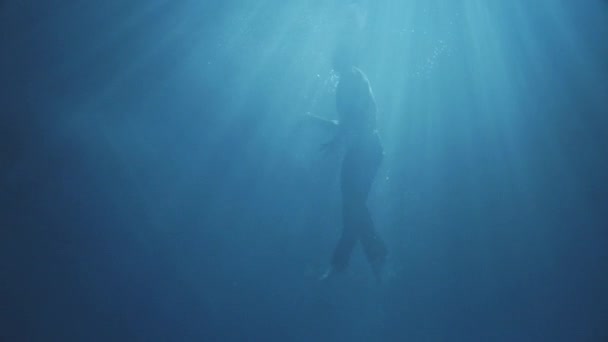 Incroyable homme habillé essayant de sortir de l'eau se déplaçant bien, dans le noir, avec un peu de lumière du soleil .