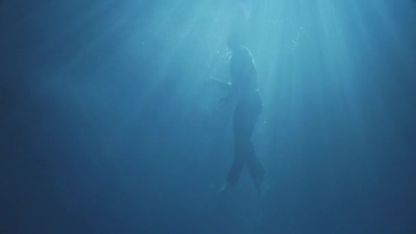 Increíble hombre vestido tratando de salir del agua moviéndose bien, en la oscuridad, con un poco de luz solar . — Vídeo de stock