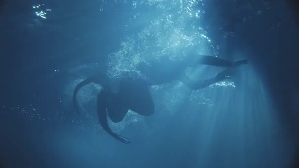 Un hombre daving en el agua oscura con algunas s de la luz del sol . — Vídeos de Stock