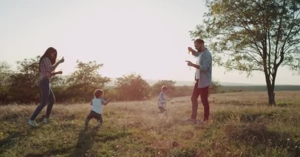 Tiempo familiar perfecto, mamá y papá haciendo burbujas para sus dos hijos, de un año y tres años de edad. 4k — Vídeos de Stock