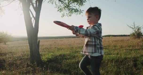 Drie jaar oude jongen speelt met vliegtuig op natuur prachtig uitzicht, zonsondergang. — Stockvideo