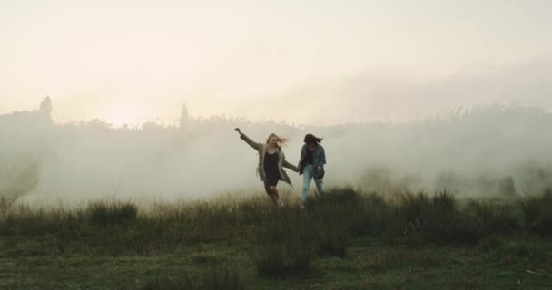 Zwei beste Freundinnen amüsieren sich in der nebligen Atmosphäre. — Stockvideo