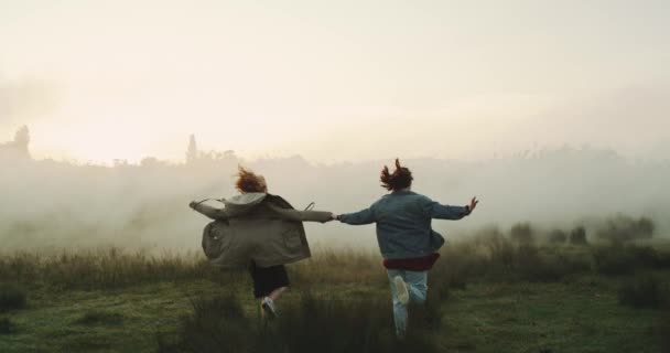 Duas meninas de cabelos bonitos pulando ao redor no horizonte verde.. movimentos lentos — Vídeo de Stock