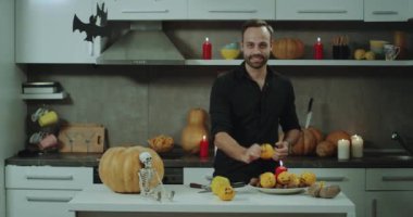 Onun mutfak, Cadılar Bayramı bir atmosfer, bir ile oynarken, kamera önünde bir sakallı bir adam turuncu süslü ve büyük bir gülümseme yüzleri.