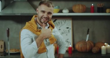 Closeup kamera önünde gülümseyen bir Cadılar Bayramı partisi önce bir adam, o ayağa mutfak masasında, arka plan şaşırtıcı Halloween süslemeleri.