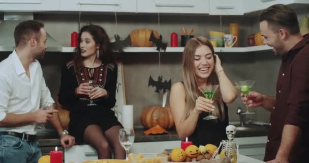 Deux beaux couples ont un drôle de moment sur la fête d'Halloween, ils ont une conversation, tenant un verre avec du vin et des cocktails, belles décorations d'Halloween autour . — Video