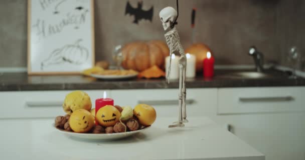 Detalles de Halloween, decoraciones, un plato con velas y un divertido esqueleto de dacing en la mesa. Disparo en la épica roja — Vídeo de stock