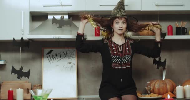 Drôle de sorcière jouant charismatique devant la caméra la nuit d'Halloween sur la cuisine, elle a un visage asiatique et les cheveux bouclés . — Video