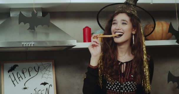 A beautiful Asian lady with a pretty face masked in a witch on Halloween night playing charismatic in front of the camera eating some snacks. — Stock Video