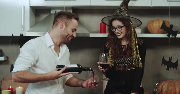 Usměvavý mladý pár na Halloween party, pití červeného vína od brýlí v kuchyni úžasné dekorace. — Stock video