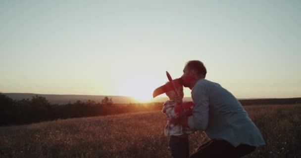 Середина поля на закате, папа со своим сыном, играет с самолетом и проводит потрясающее время вместе . — стоковое видео
